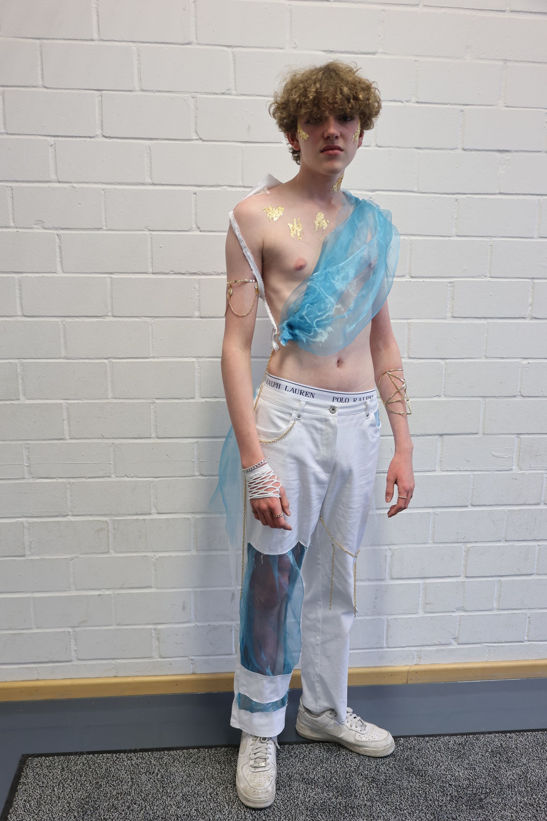 Look in Weiß und Hellblau mit transparenter Schärpe über weißer Hose.