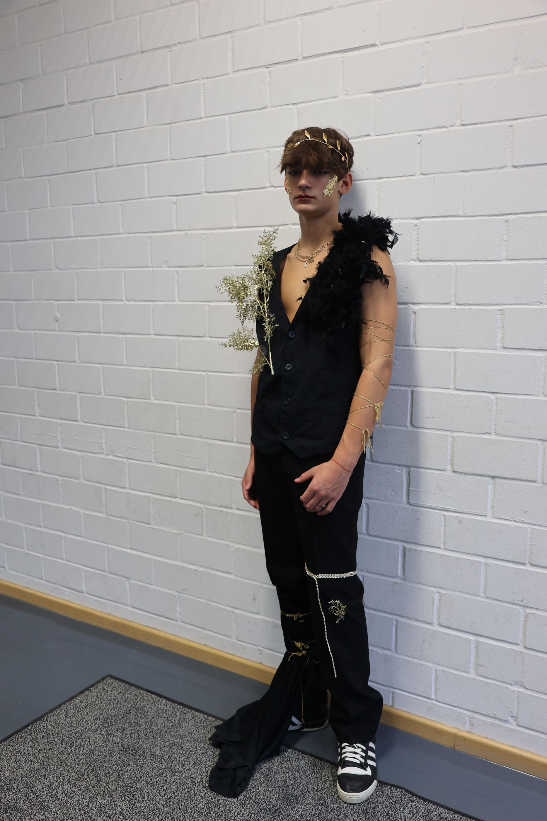 Look ganz in Schwarz mit Federbesatz und goldenem Kopfschmuck.