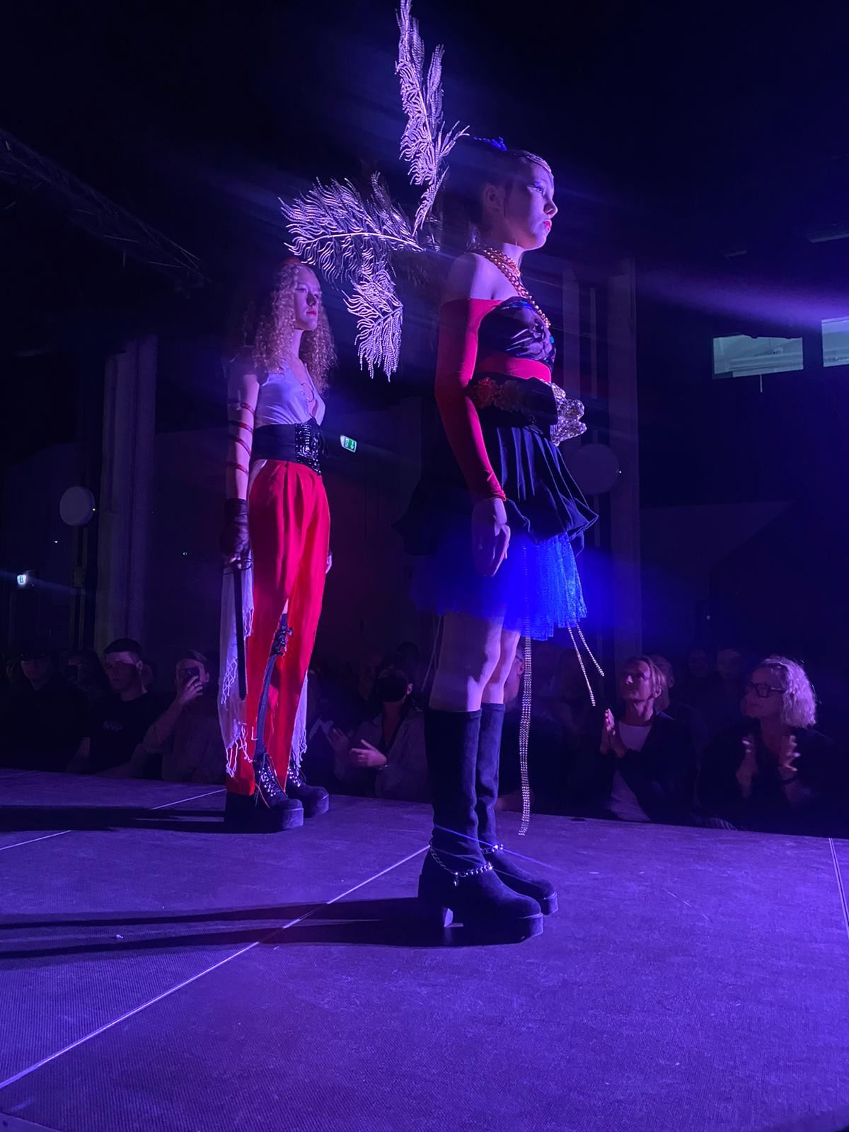 Zwei Models unter violettem Bühnenlicht während der Show.
