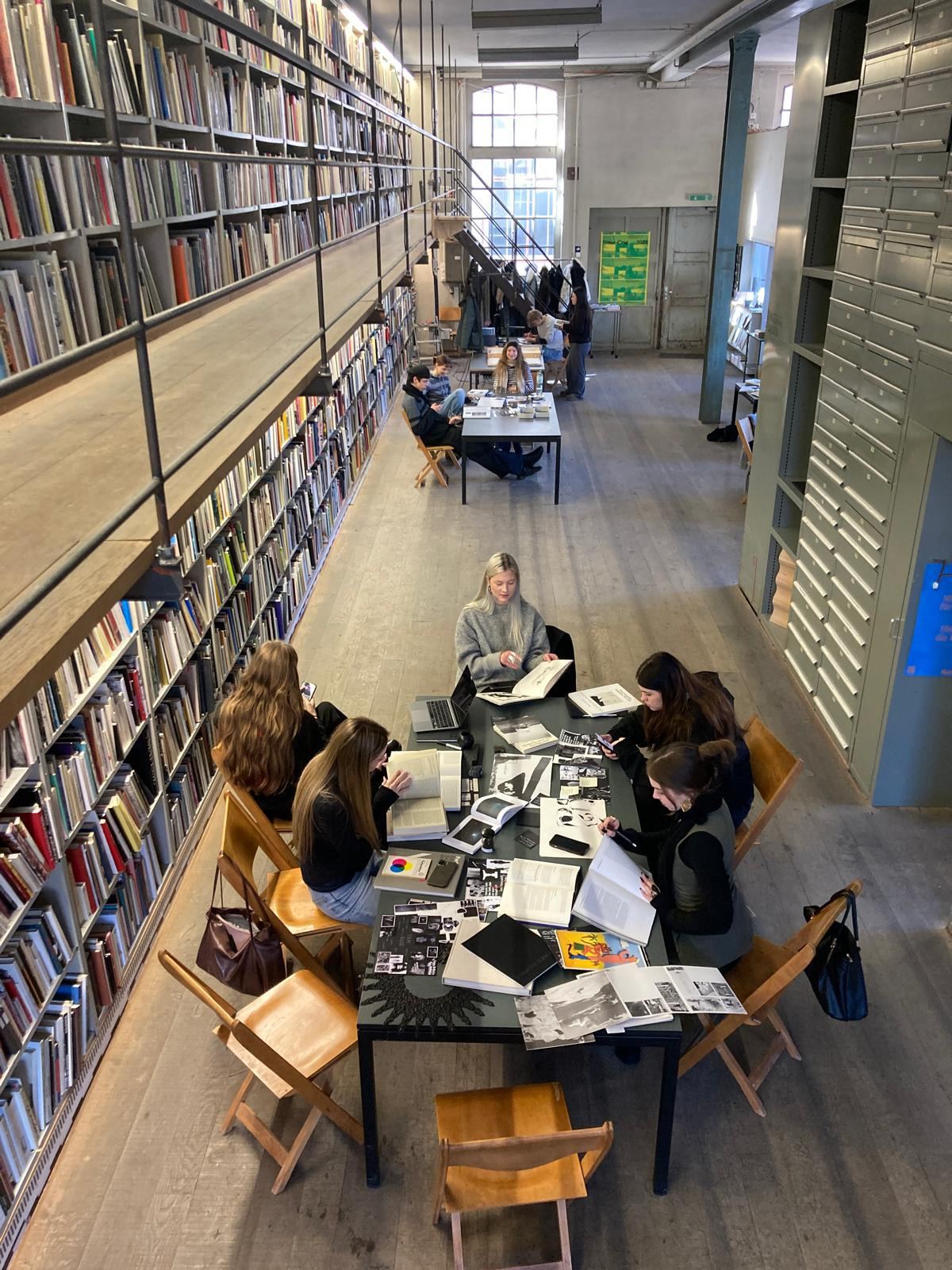 Arbeitsgruppe an einem Tisch in der Bibliothek, ringsum Regale bis zur Decke.