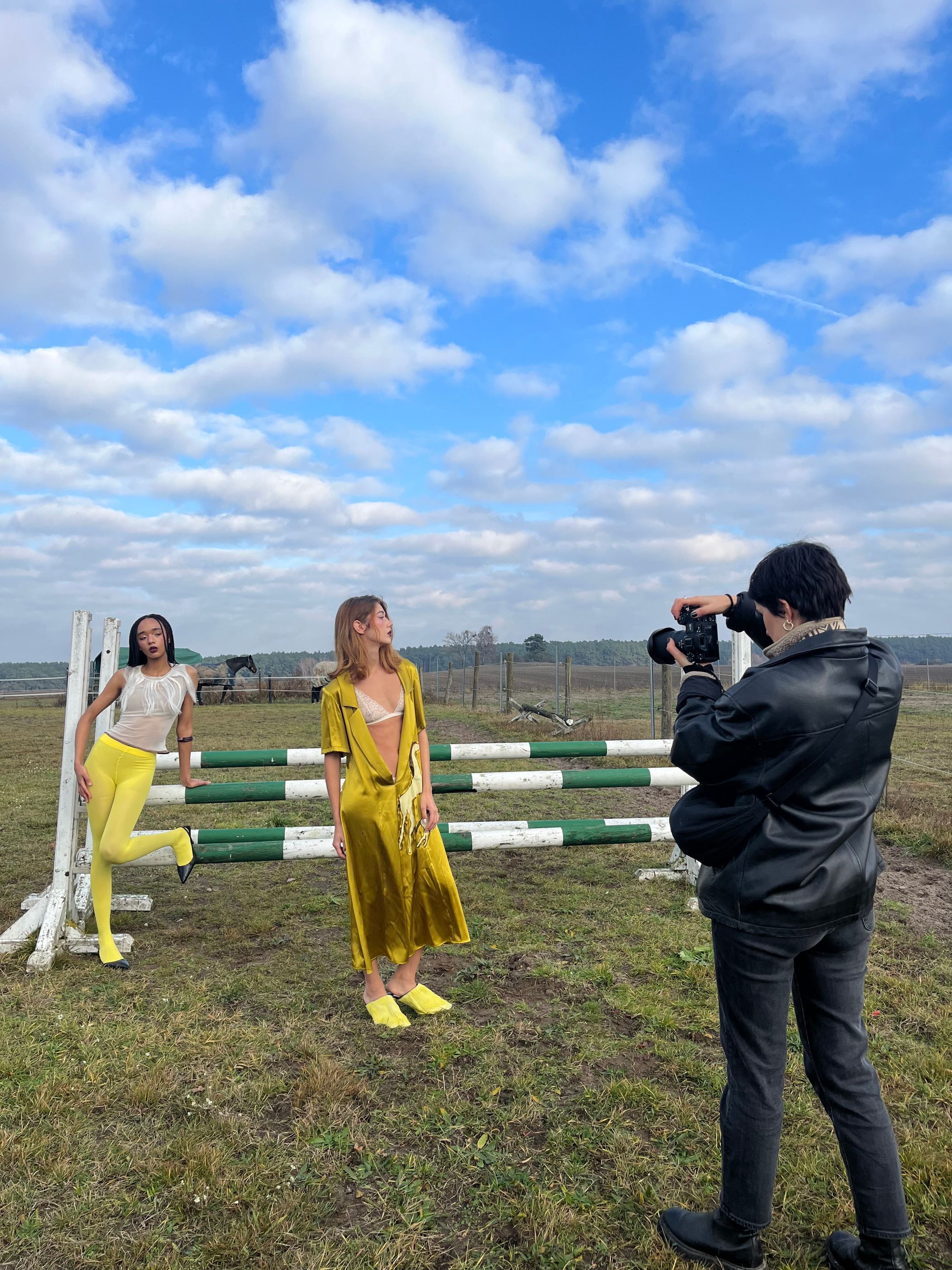 Der Fotograf im Vordergrund, zwei Models posieren am Sprunghindernis auf der Koppel.