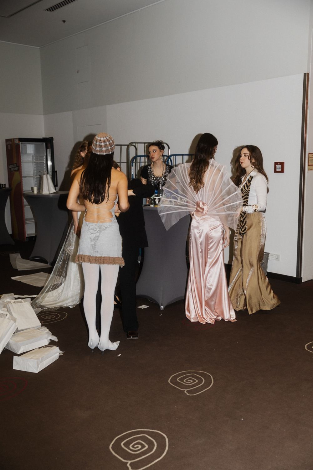 Models in ihren Looks warten backstage nebeneinander auf den Auftritt.