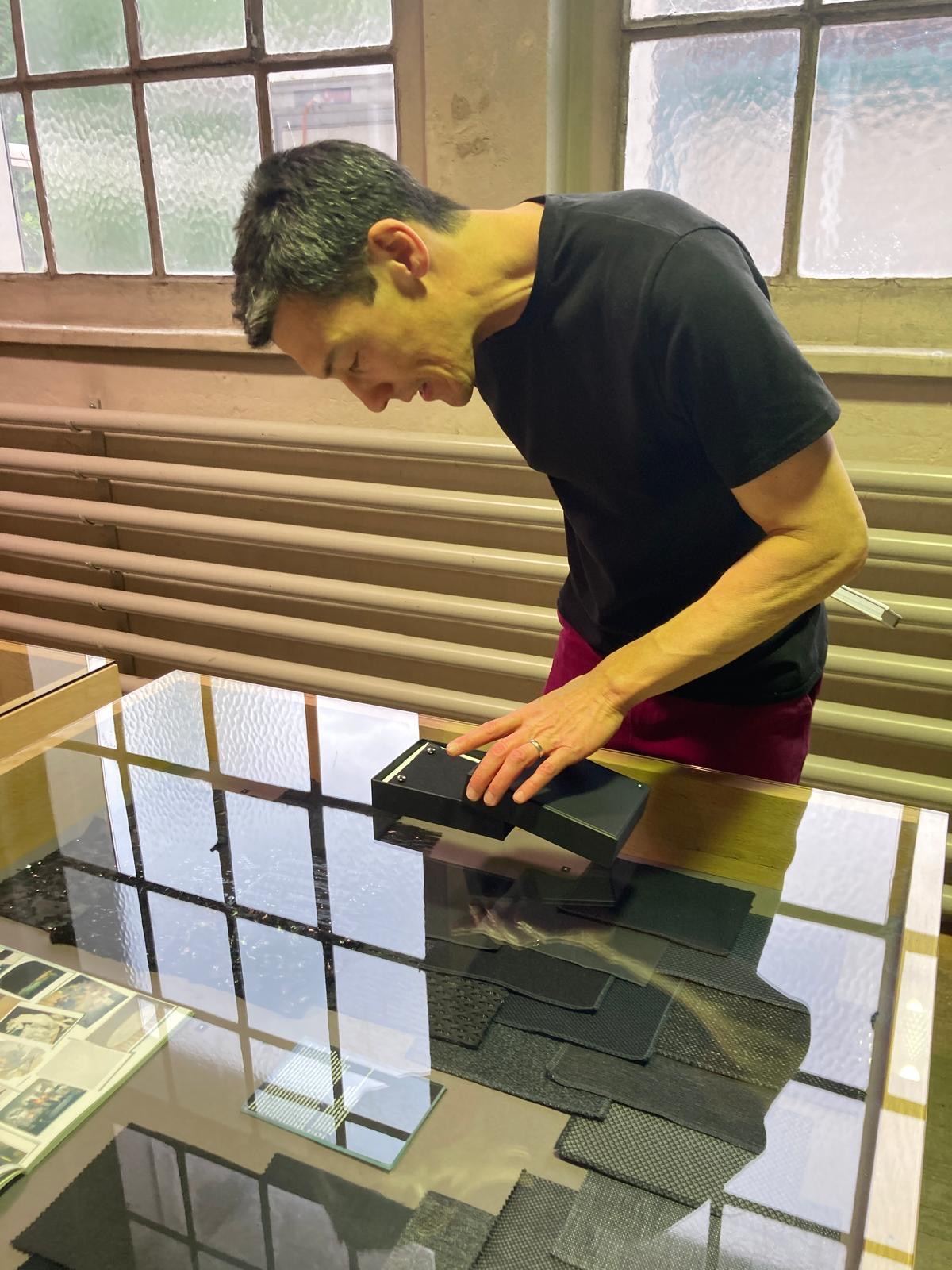 Eine Person beugt sich über eine Vitrine und richtet ein Exponat.