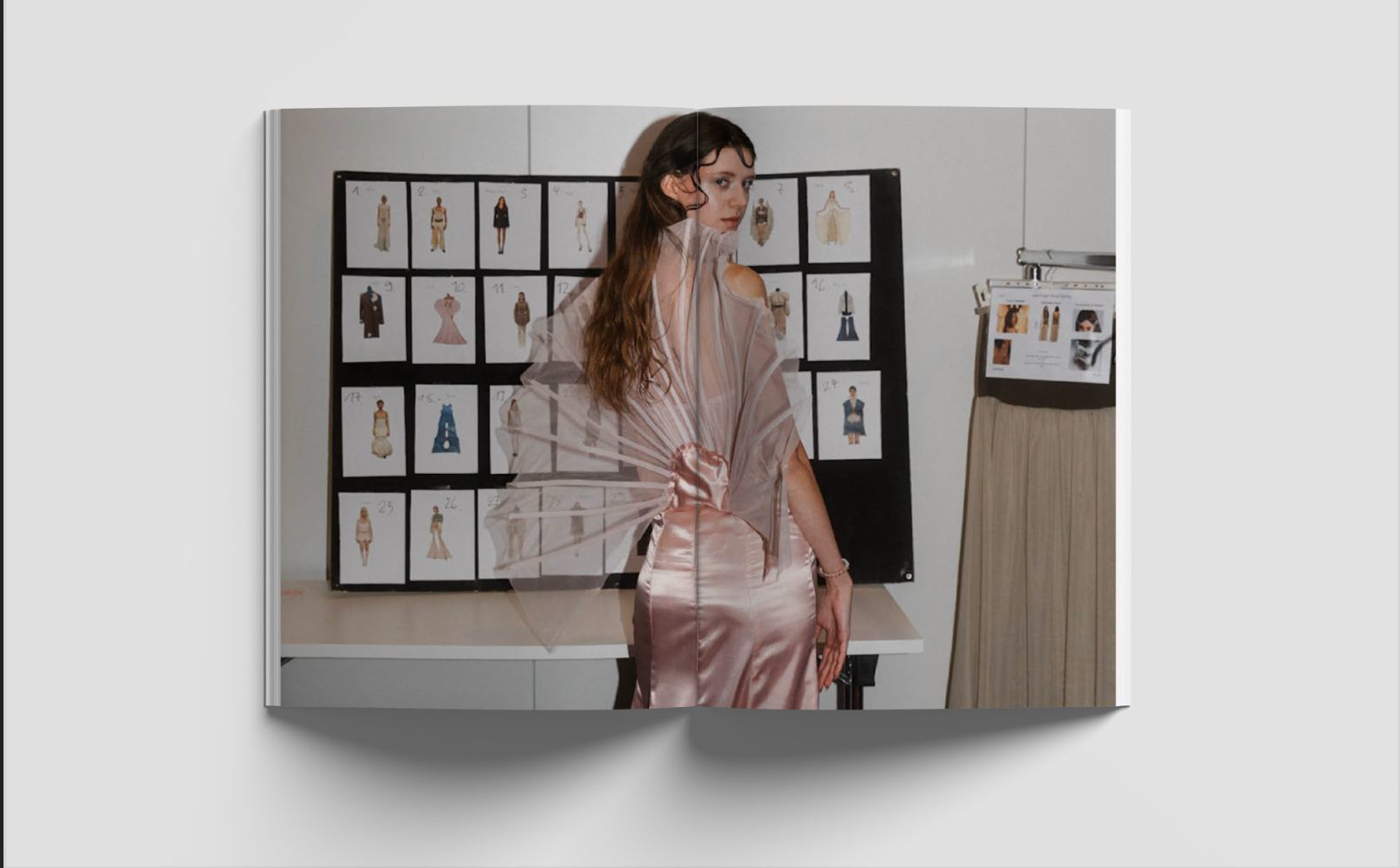 Lookbook-Doppelseite: das Model im rosa Look vor einer Tafel mit allen Entwurfszeichnungen der Kollektion.